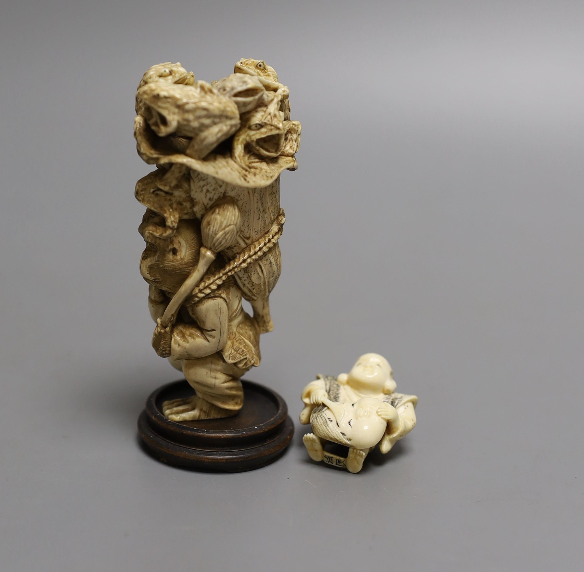 A Japanese ivory okimono of a monkey carrying a lotus leaf containing toads, on its back and an Ivory Netsuke of a mask maker, both Meiji period - tallest 9.5cm high